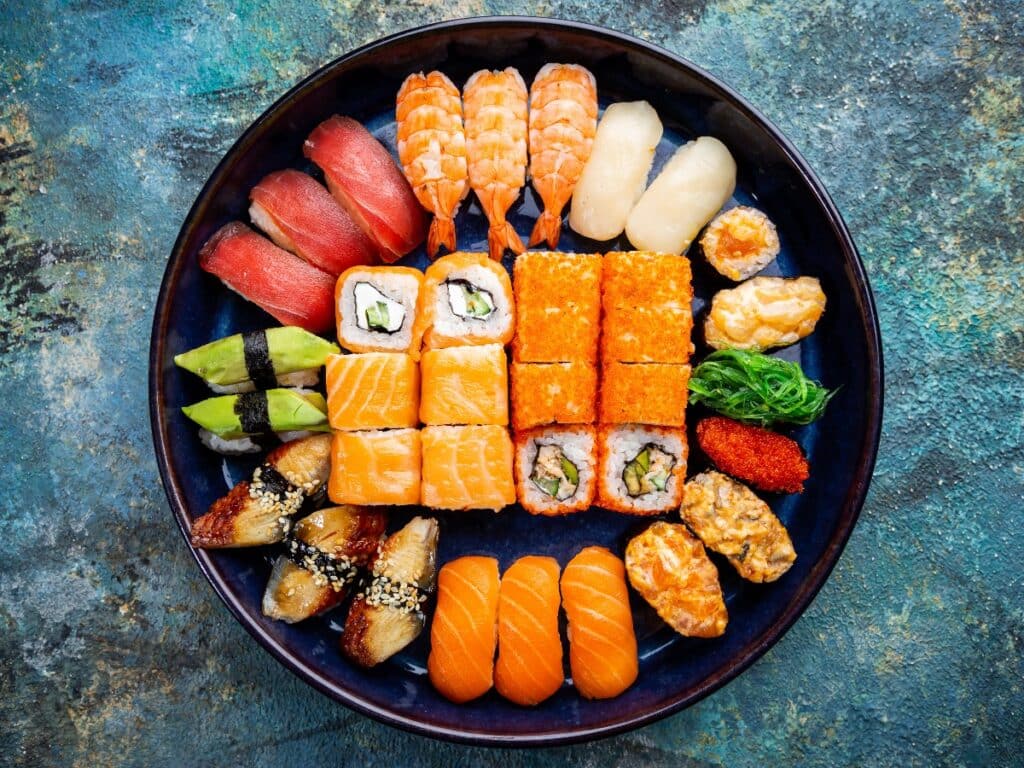 Set of sushi and maki with soy sauce over blue stone background. Top view with copy space